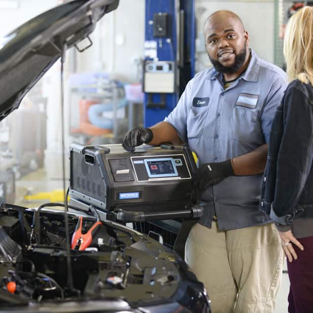 A technician standing next to a Midtronics diagnostic charging system