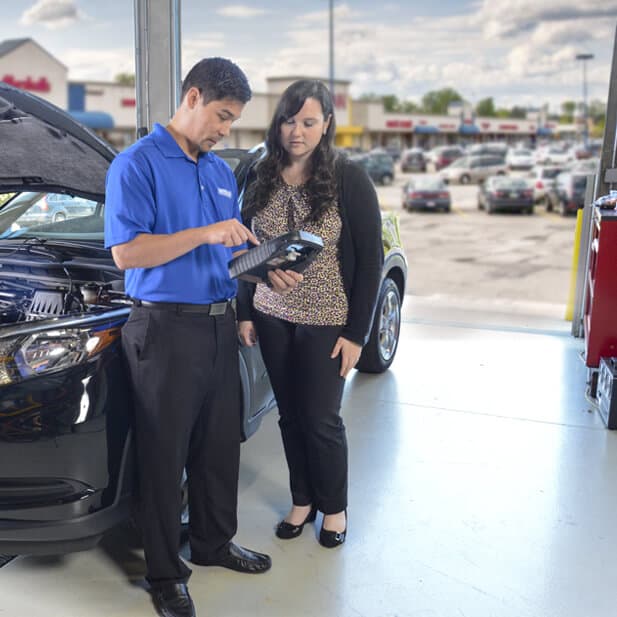 A technician showing a customer battery test results on a Midtronics battery tester