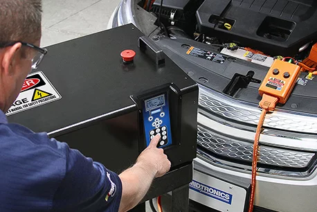 A technician using Midtronics diagnostic charger to test a car battery
